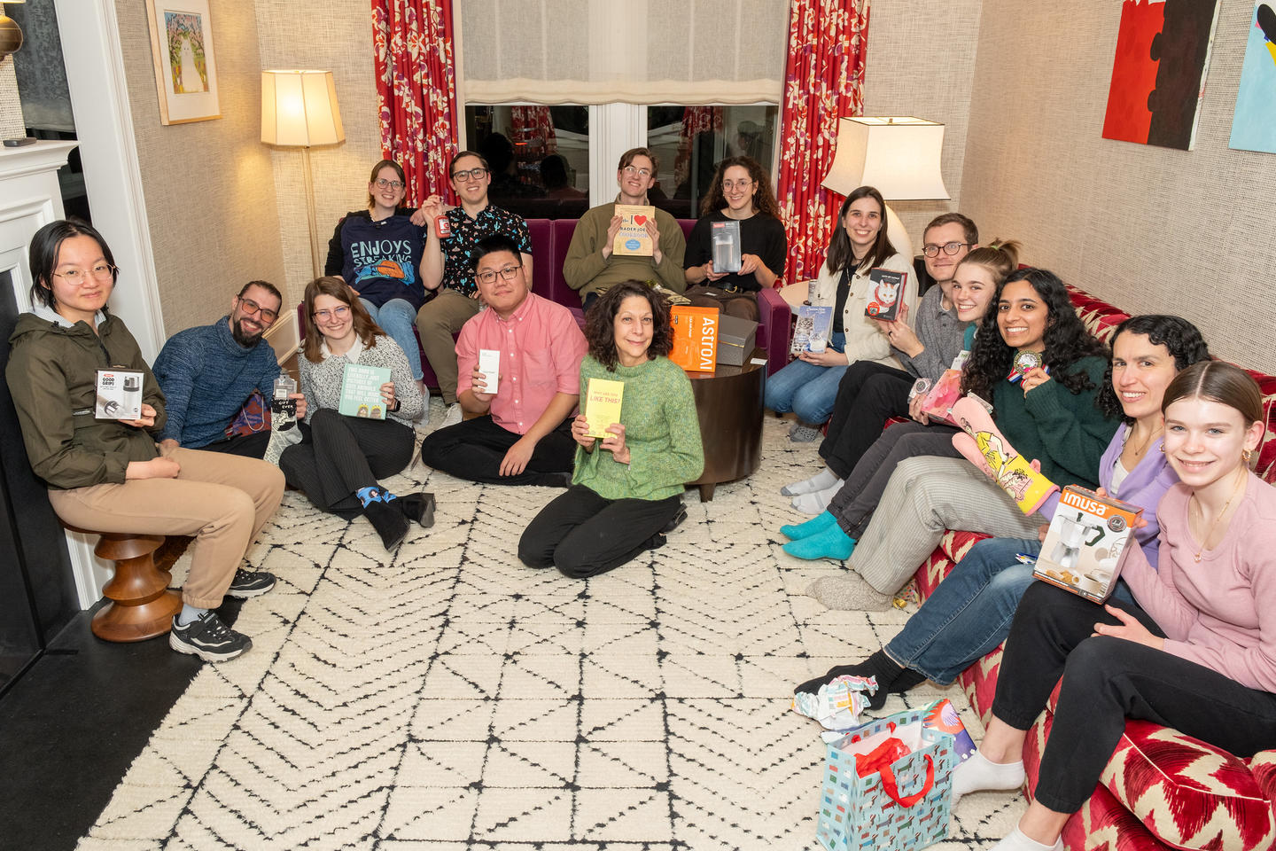 Bassler lab members gathered in a living room holding up white elephant gift exchange gifts