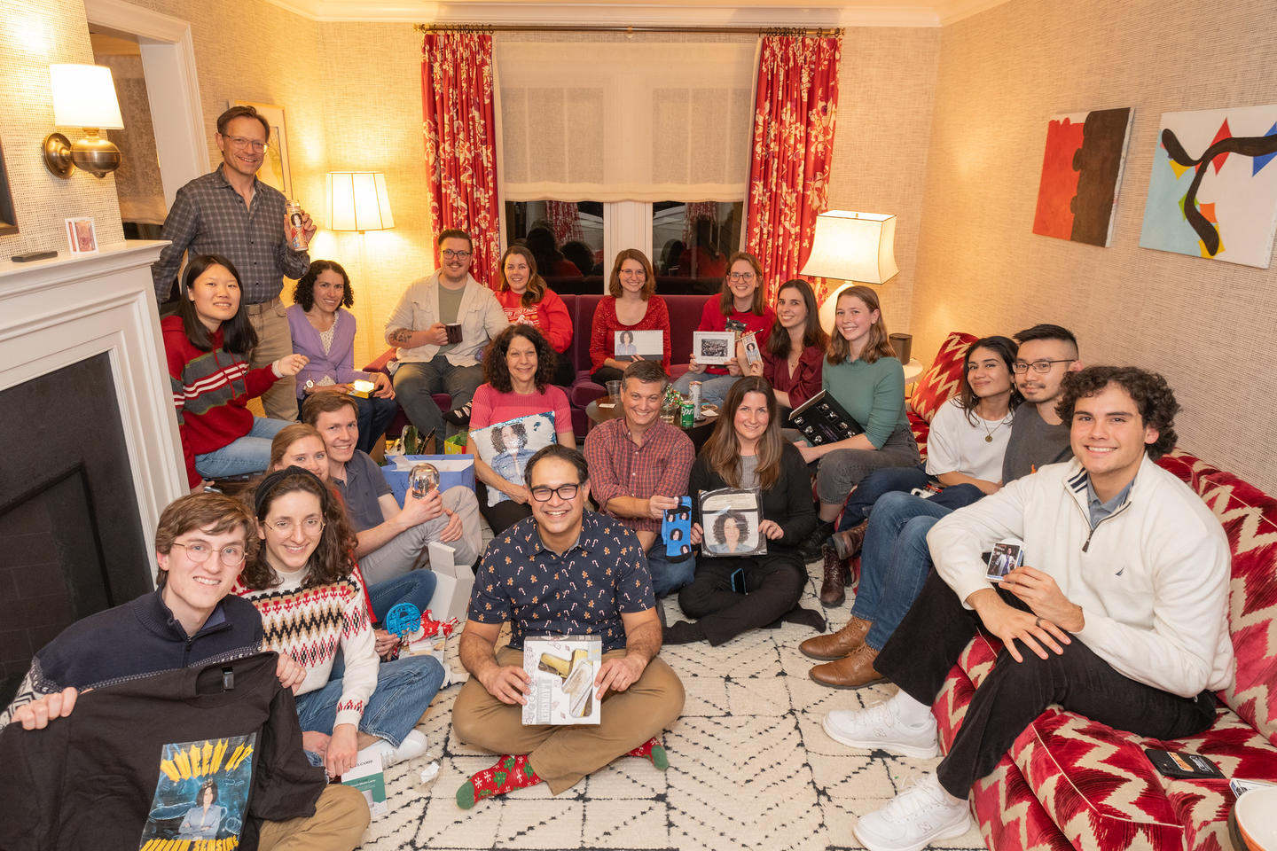 Bassler lab members gathered in a living room displaying white elephant gift exchange gifts, all of which have Bonnie's face on them